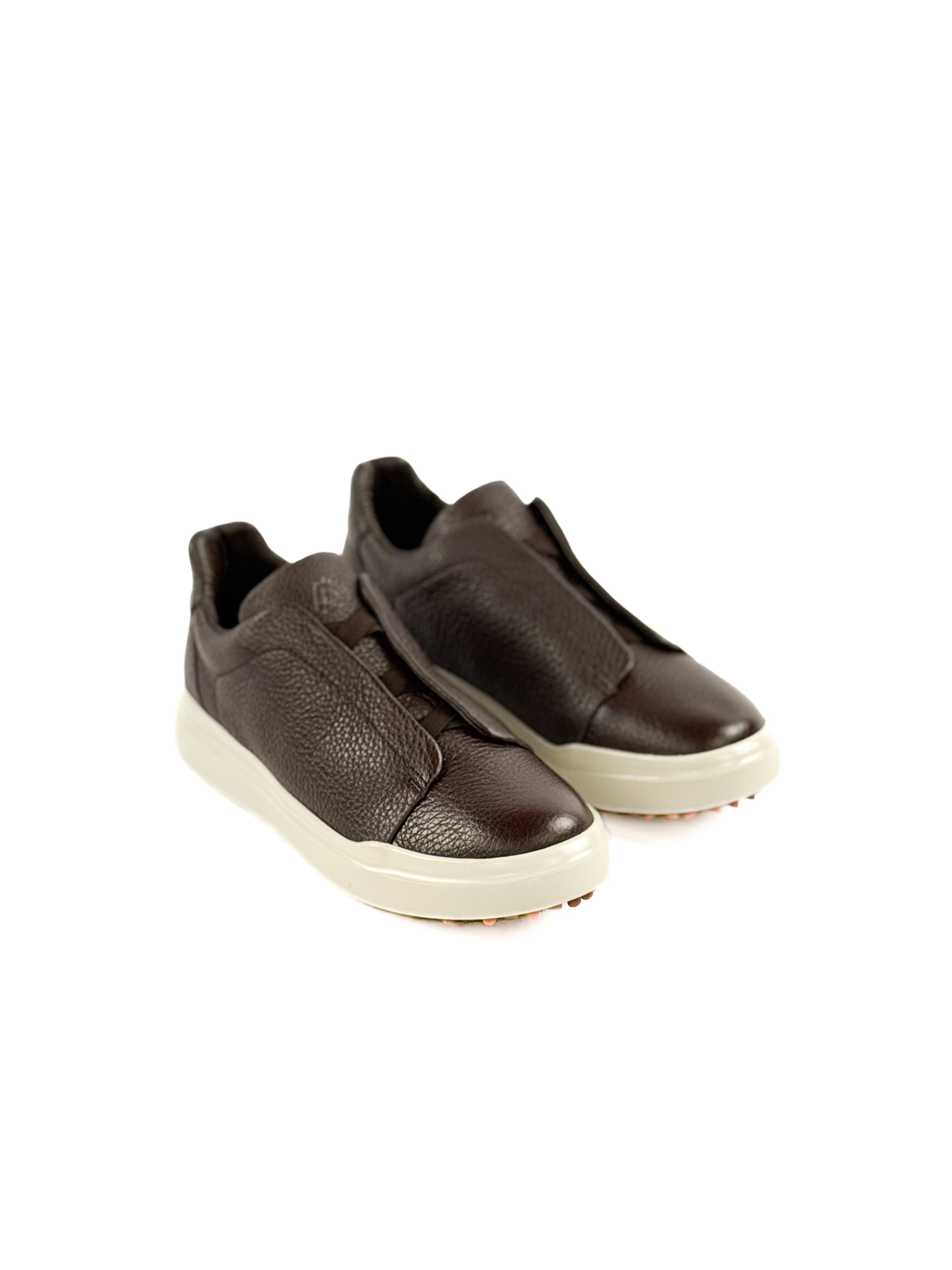 Pair of brown slip-on sneakers on a white background