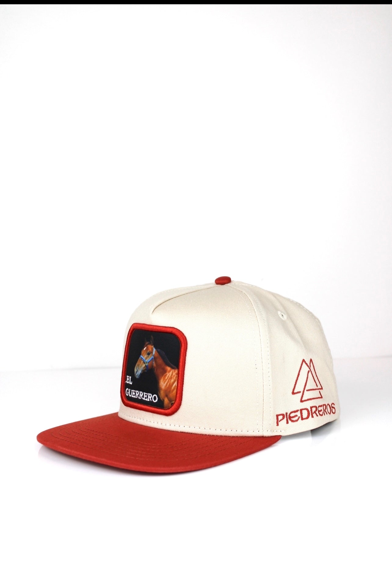 A beige and red baseball cap with 3D embroidered text and an image of el guerrero horse on the front.