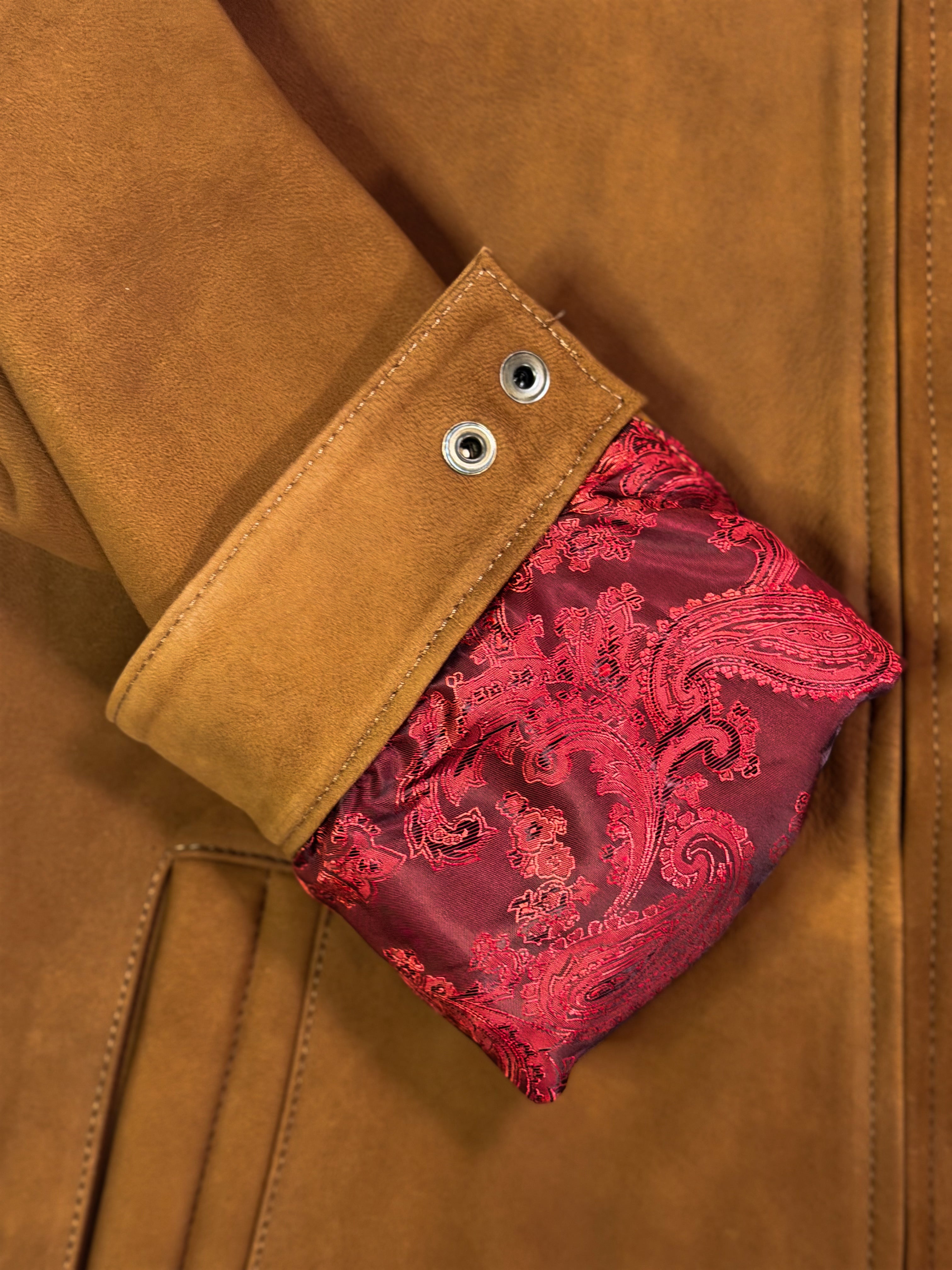 Close-up of a brown leather jacket with a red decorative inside sleeve