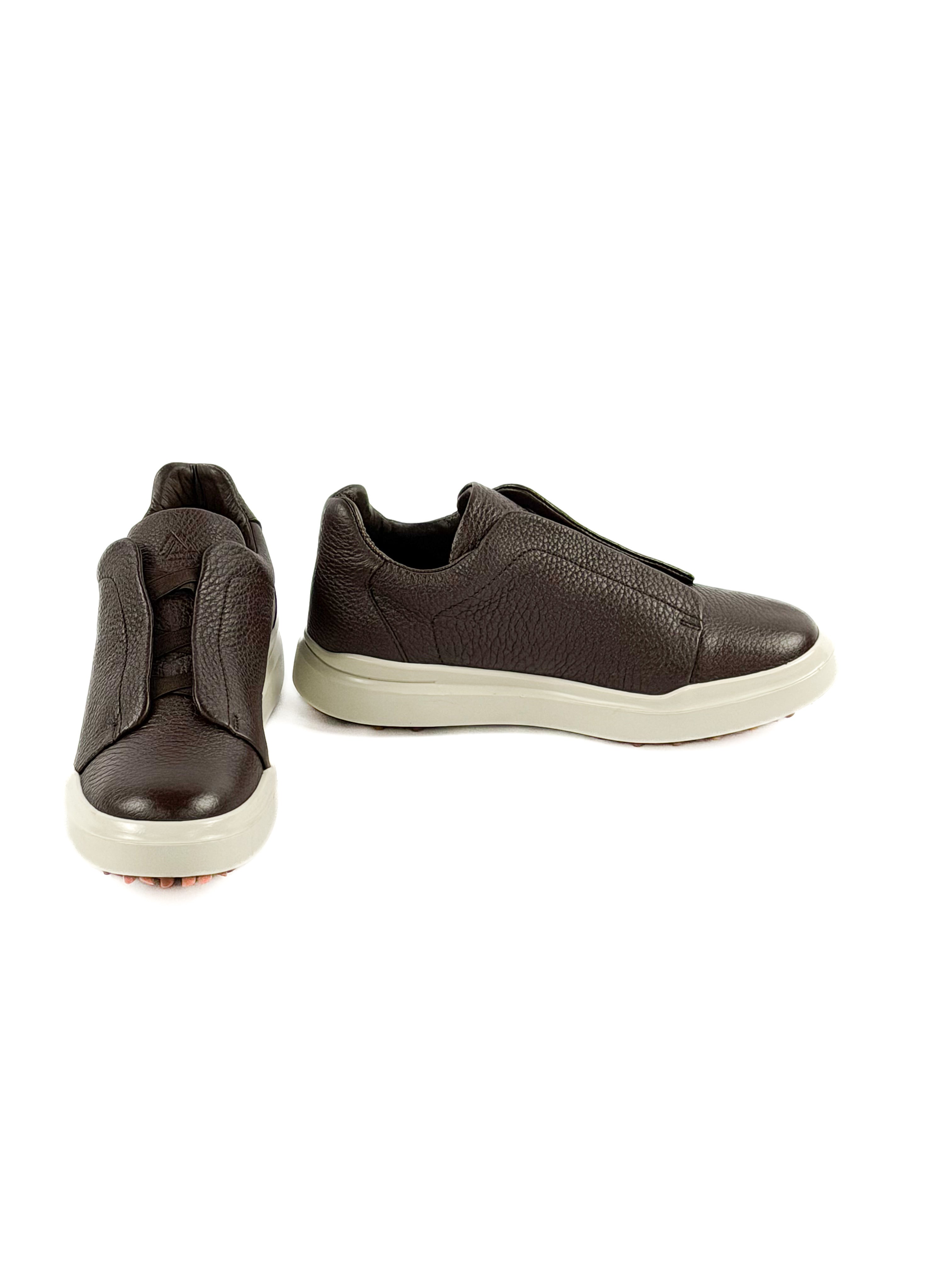Pair of brown slip-on sneakers on a white background