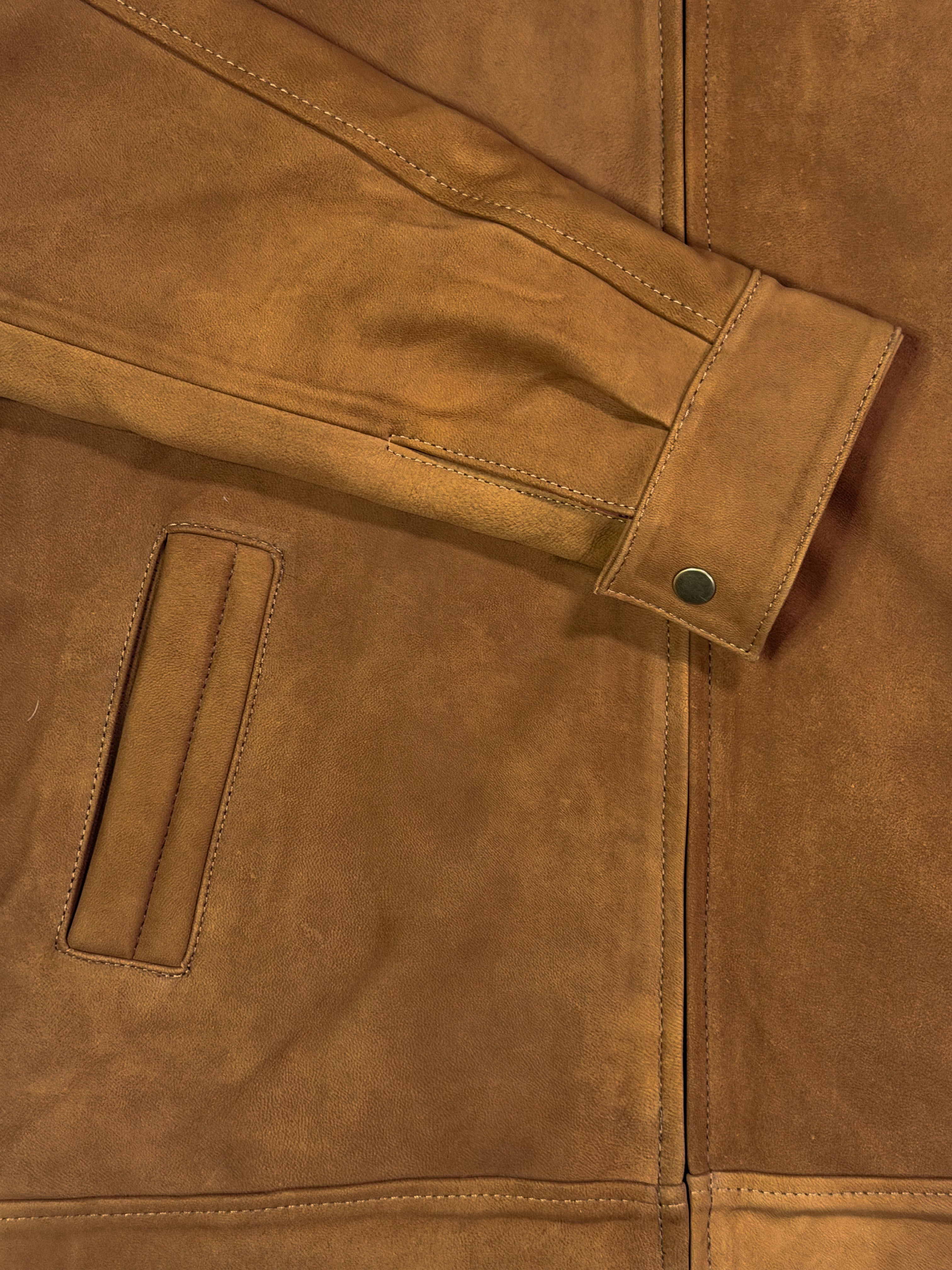 Close-up of the sleeve on a golden brown leather jacket 